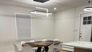 Una cocina moderna con una mesa de comedor de madera, sillas blancas y taburetes negros.
