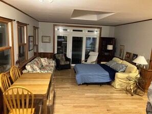 A room with a wooden dining table, two sofas, a bed, and a glass coffee table. - Creekside Retreat-spacious cottage nestled in the wildflowers and lush woods (Harleysville)