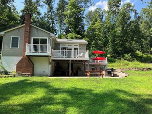 A two-story house with a balcony and a covered patio area. - Creekside Retreat-spacious cottage nestled in the wildflowers and lush woods (Harleysville)
