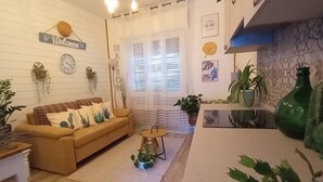 Una sala de estar acogedora con un sofá, una mesa de centro y un comedor con barra de cocina.