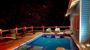 Una piscina con sillas de descanso y una terraza.