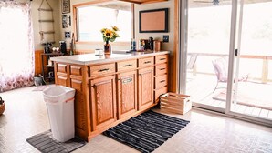 A kitchen with wooden cabinets, a sink, and a window with a view of the outdoors. - Des Moines River Front Cabin- Fishing/Hunting/Kayaking (Keosauqua)
