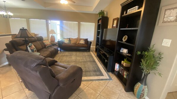 A living room with a sectional sofa, a black entertainment unit, and a potted plant.
