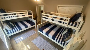 A room with two bunk beds, a door, and a small rug.