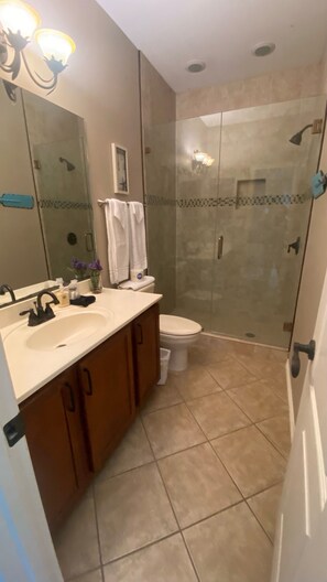 A bathroom with a sink, toilet, and glass-enclosed shower.