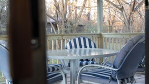 A covered outdoor seating area with a round table and striped chairs.