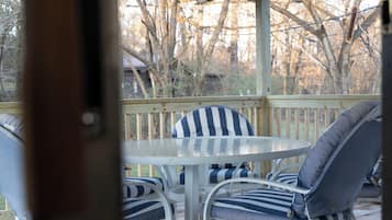 Relax in a serene outdoor seating area with a round table and four comfortable chairs, surrounded by a deck with a picturesque view.