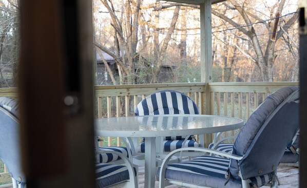 Relax in a serene outdoor seating area with a round table and four comfortable chairs, surrounded by a deck with a picturesque view.
