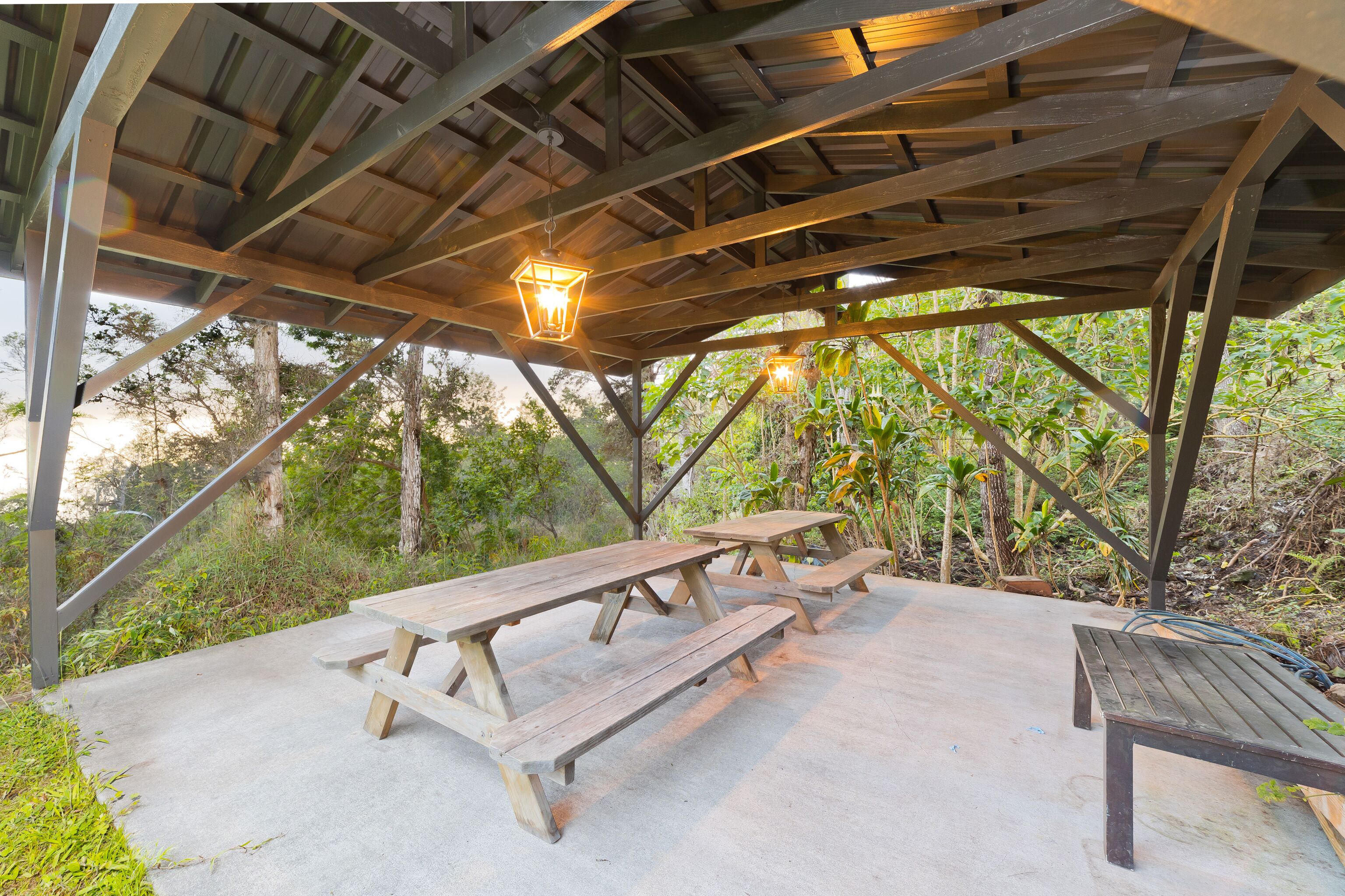 An outdoor wooden pavilion with picnic tables and hanging lanterns.