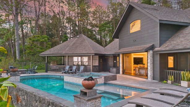 Une maison moderne dotée d’une piscine, d’un espace salon extérieur et d’un patio couvert.