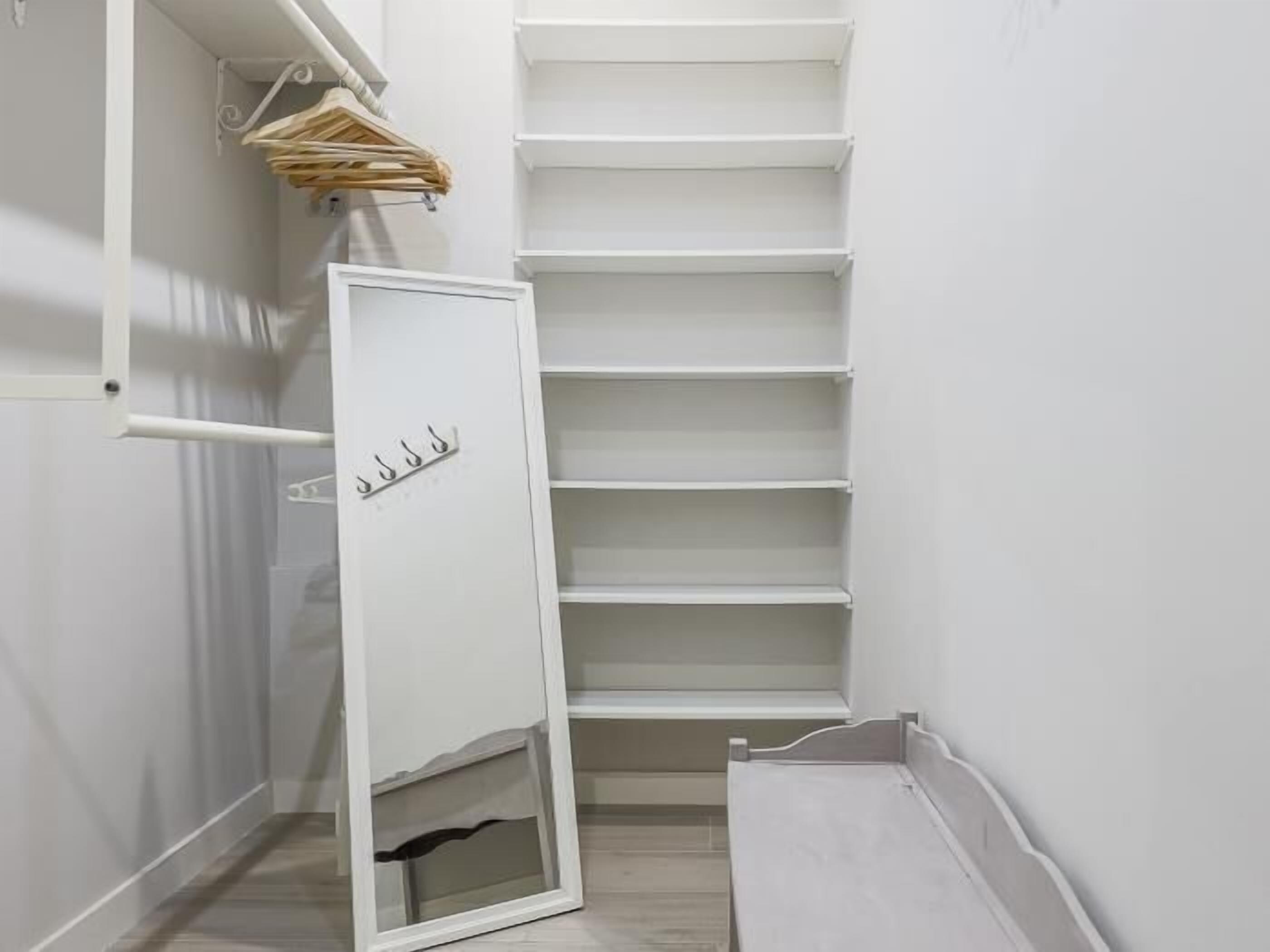 A white closet with multiple shelves and a hanging rod.