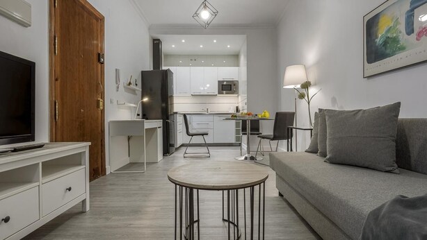 A modern living room with a grey sofa, a TV, and a dining area with a table and chairs. - Studio with charm at the historic center. WIFI/AC (Sevilla)