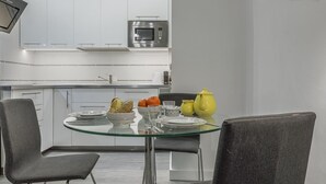 A modern kitchen with white cabinets, a built-in microwave, and a glass dining table with chairs. - Studio with charm at the historic center. WIFI/AC (Sevilla)