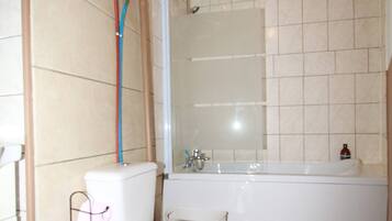 Een bad/douchecombinatie, een haardroger, handdoeken