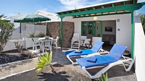 A patio with lounge chairs, a table, and an umbrella. - Apartment 'Jardin del Sol 26' with Terrace, Shared Pool& Wi-Fi (Playa Blanca)