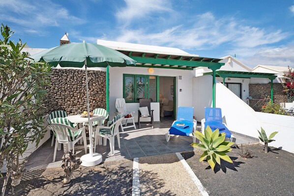 A patio with outdoor furniture, a stone wall, and a covered area with a door.
