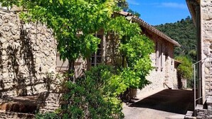 A stone building with a tiled roof, a small tree in front, and a clear blue sky. - Charming renovated sheepfold in a natural setting, not overlooked, private swimming pool (La penne sur l'ouveze)