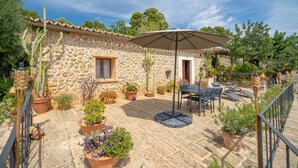 A stone building with a patio, outdoor seating, and potted plants. - Country Home "Can Pulit" with Pool, Garden, A/C & Wi-Fi (Selva)