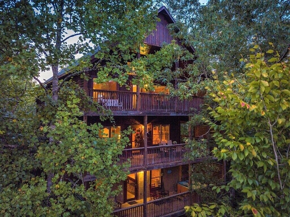 A multi-story wooden cabin surrounded by dense foliage.