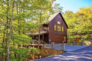 A wooden cabin with a balcony, surrounded by trees.
