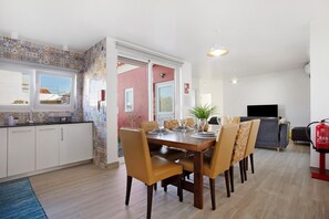 A dining area with a wooden table and chairs, a TV, and a fire extinguisher.