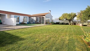 Una casa moderna con un césped cuidado, un patio y un amplio ventanal que da a un espacio exterior cubierto.