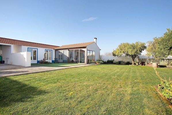 A modern house with a well-maintained lawn, a patio, and a large glass door leading to a covered outdoor area.