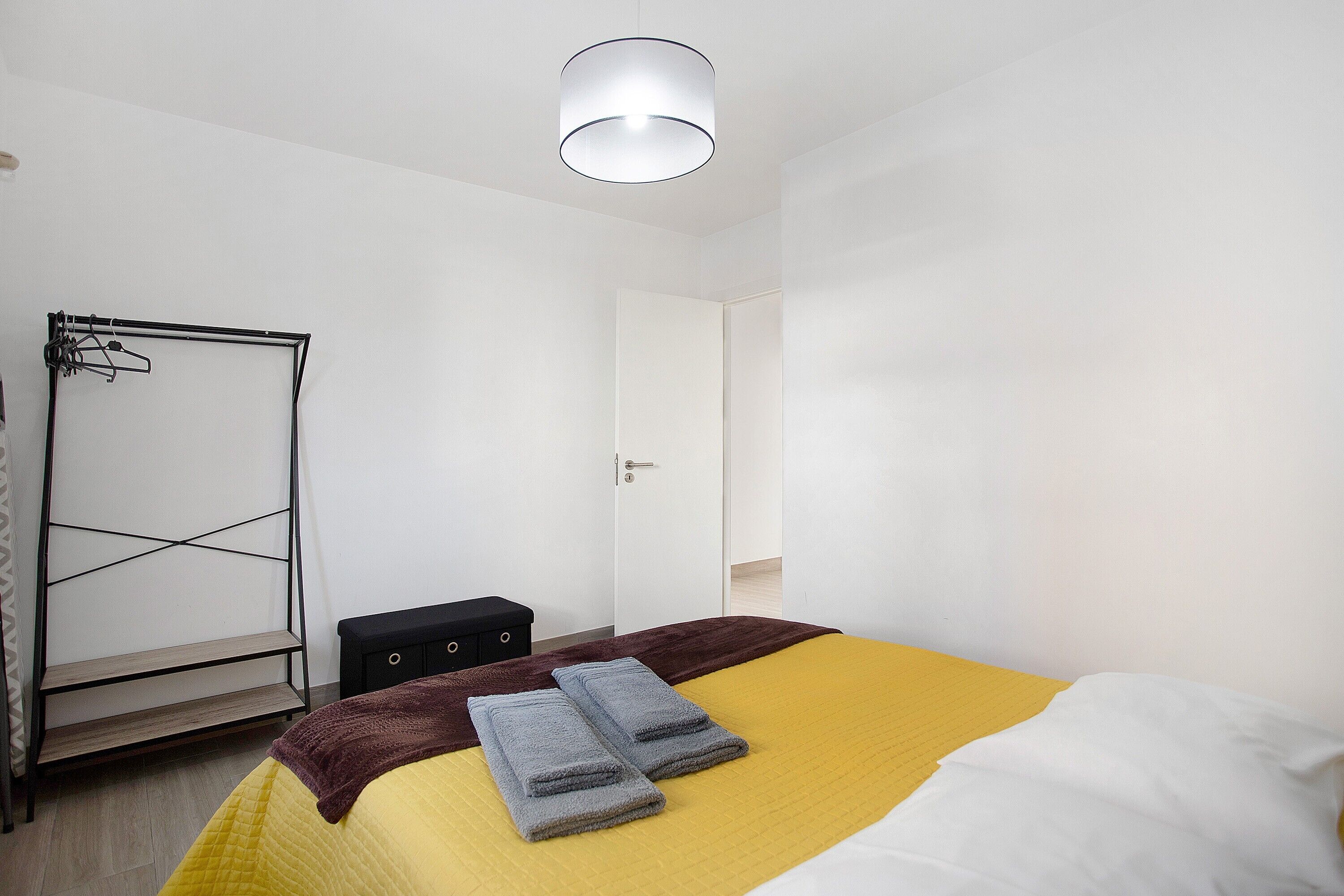 Un dormitorio con cama, armario, perchero y puerta.
