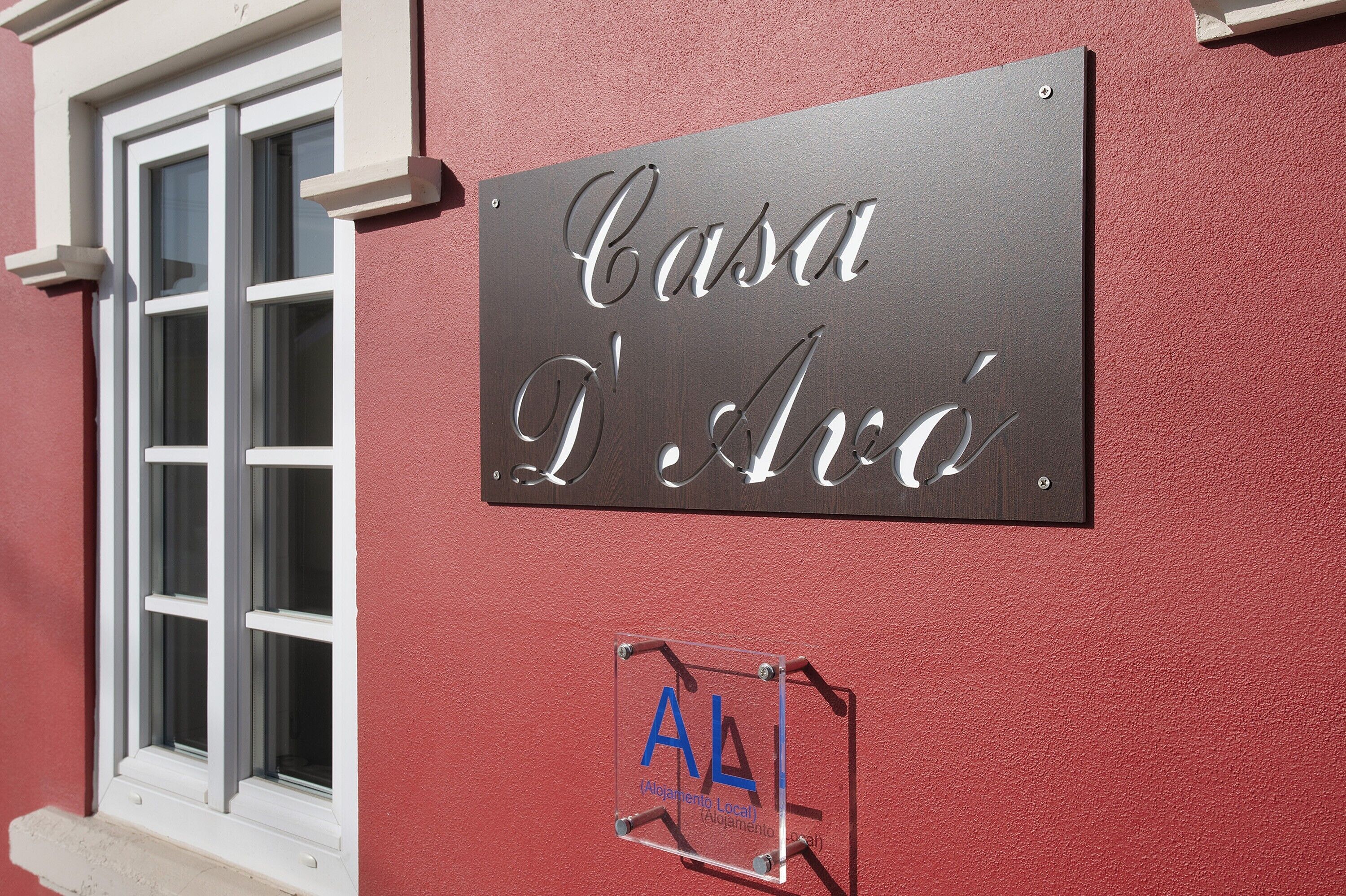 A sign with 'Casa D'Avó' and a logo with 'AL' on a red wall.