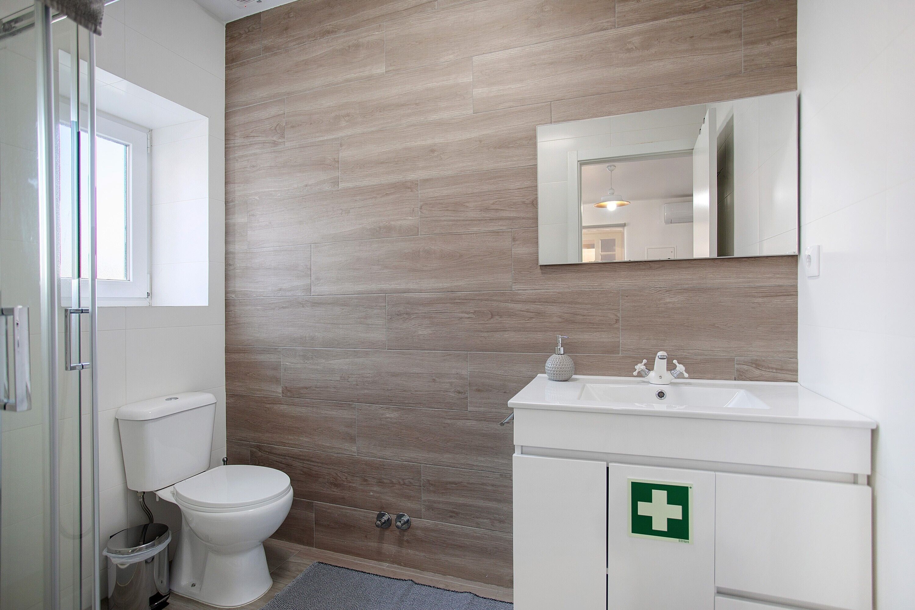 A bathroom with a toilet, sink, and mirror.