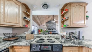 Une cuisine avec des meubles en bois, un plan de travail en granit, une cuisinière et un pare-feu en pierre.