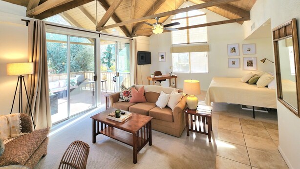 A spacious living area with a high ceiling, a sofa, a coffee table, and a bed. - Peaceful Desert Studio Condo near La Quinta & Palm Desert.  Tons to do! (Indian Wells)