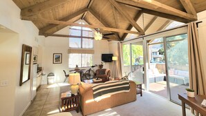 A spacious living room with a high ceiling, a sofa, a table, and a bicycle. - Peaceful Desert Studio Condo near La Quinta & Palm Desert.  Tons to do! (Indian Wells)