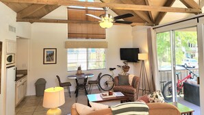 A spacious living area with a high ceiling, a dining table, and a television. - Peaceful Desert Studio Condo near La Quinta & Palm Desert.  Tons to do! (Indian Wells)