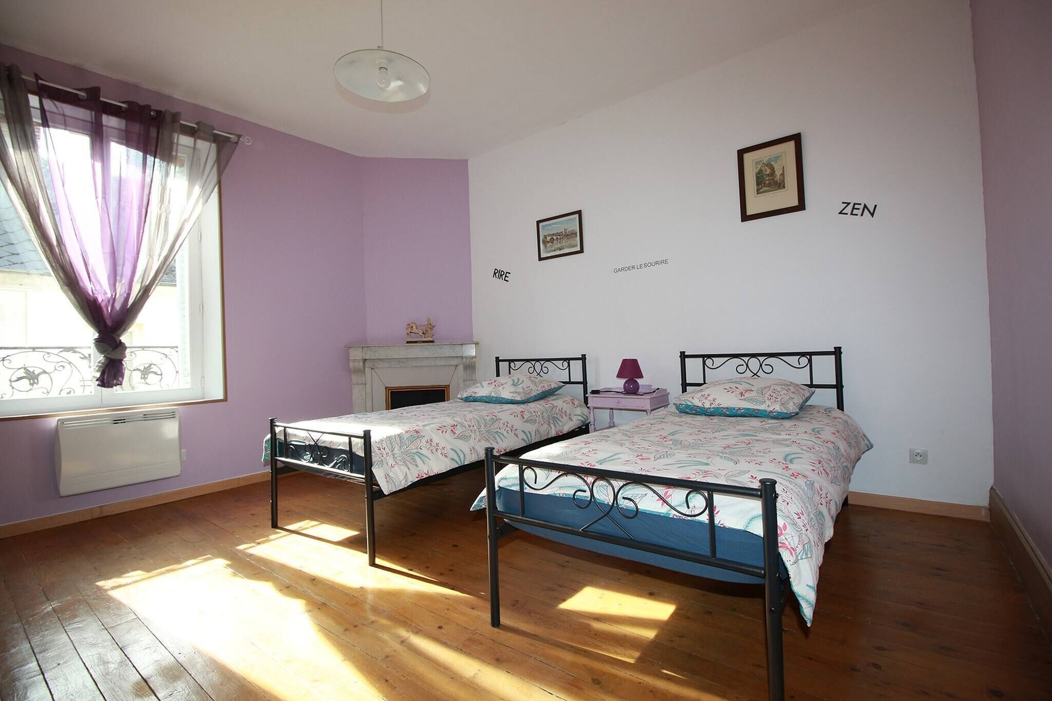 Un dormitorio con dos camas de metal, una ventana con cortinas, una chimenea y una pared con un cuadro y texto.