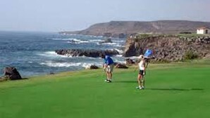 A golf course with a view of the ocean and rocky cliffs.