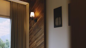 Eine Holzwand mit querverlaufenden Lamellen, einer Wandleuchte und einem Lüftungsgitter.