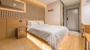 Une chambre à coucher moderne avec une tête de lit en bois, une table de chevet avec une lampe et une porte donnant sur une salle de bain.