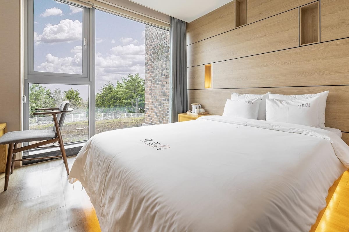 Une chambre d’hôtel moderne, dotée d’un grand lit, d’un bureau et offrant une vue sur l’extérieur.