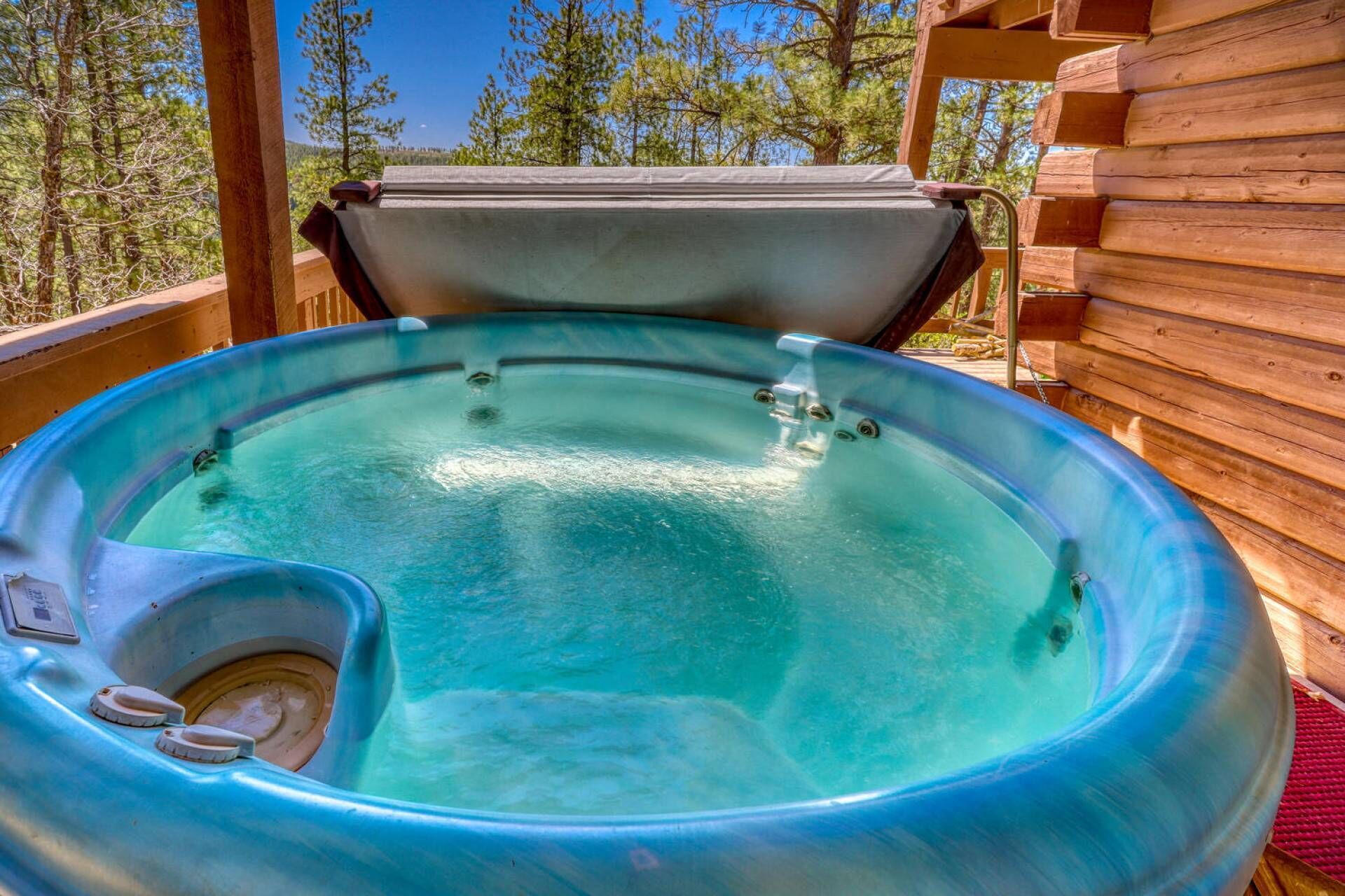 A hot tub in a wooden cabin with a clear view of the surrounding forest.