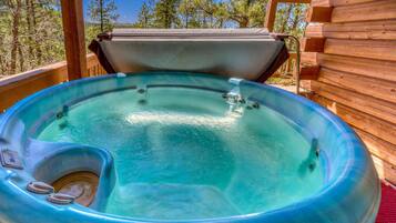 A hot tub in a wooden cabin with a clear view of the surrounding forest.