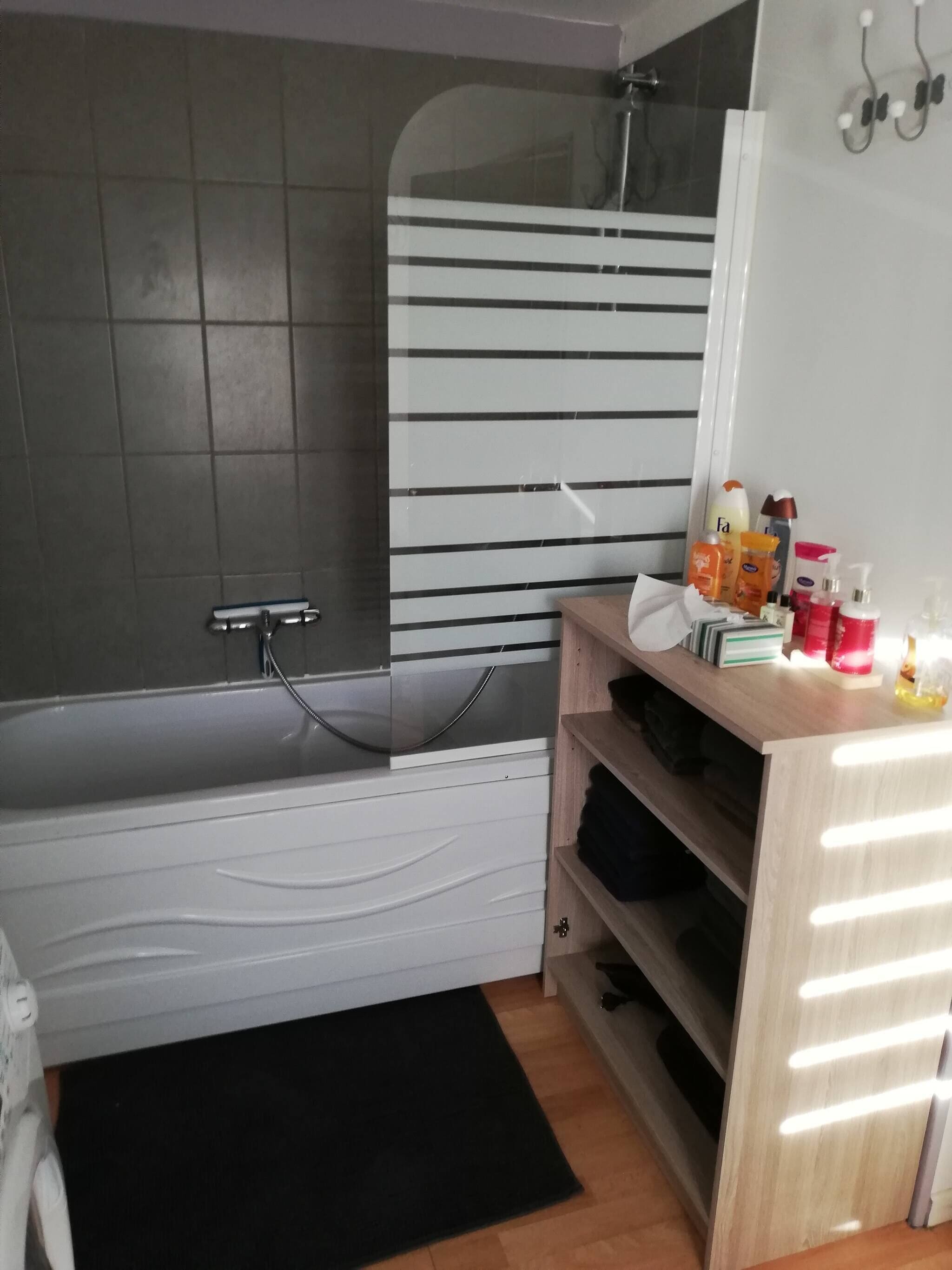 Een bad/douchecombinatie, een haardroger, handdoeken