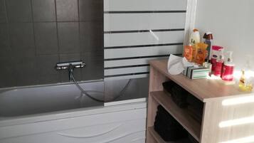 Een bad/douchecombinatie, een haardroger, handdoeken