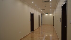 A long, well-lit hallway with marble flooring and doors on both sides. - Karim Hotel (Ras Tanura)