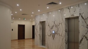A modern hotel lobby with marble walls, two elevators, and a polished floor. - Karim Hotel (Ras Tanura)