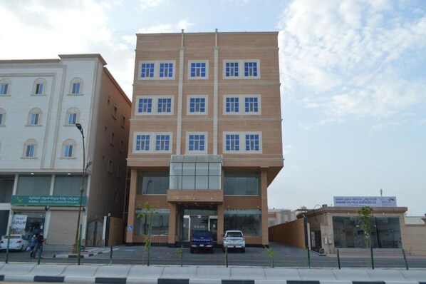 A multi-story building with a central entrance, surrounded by smaller buildings. - Karim Hotel (Ras Tanura)