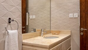 A bathroom with a marble sink, wooden door, and a towel rack. - Karim Hotel (Ras Tanura)