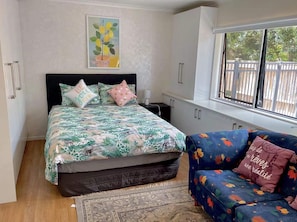 A bedroom with a bed, a window, a sofa, and a rug.