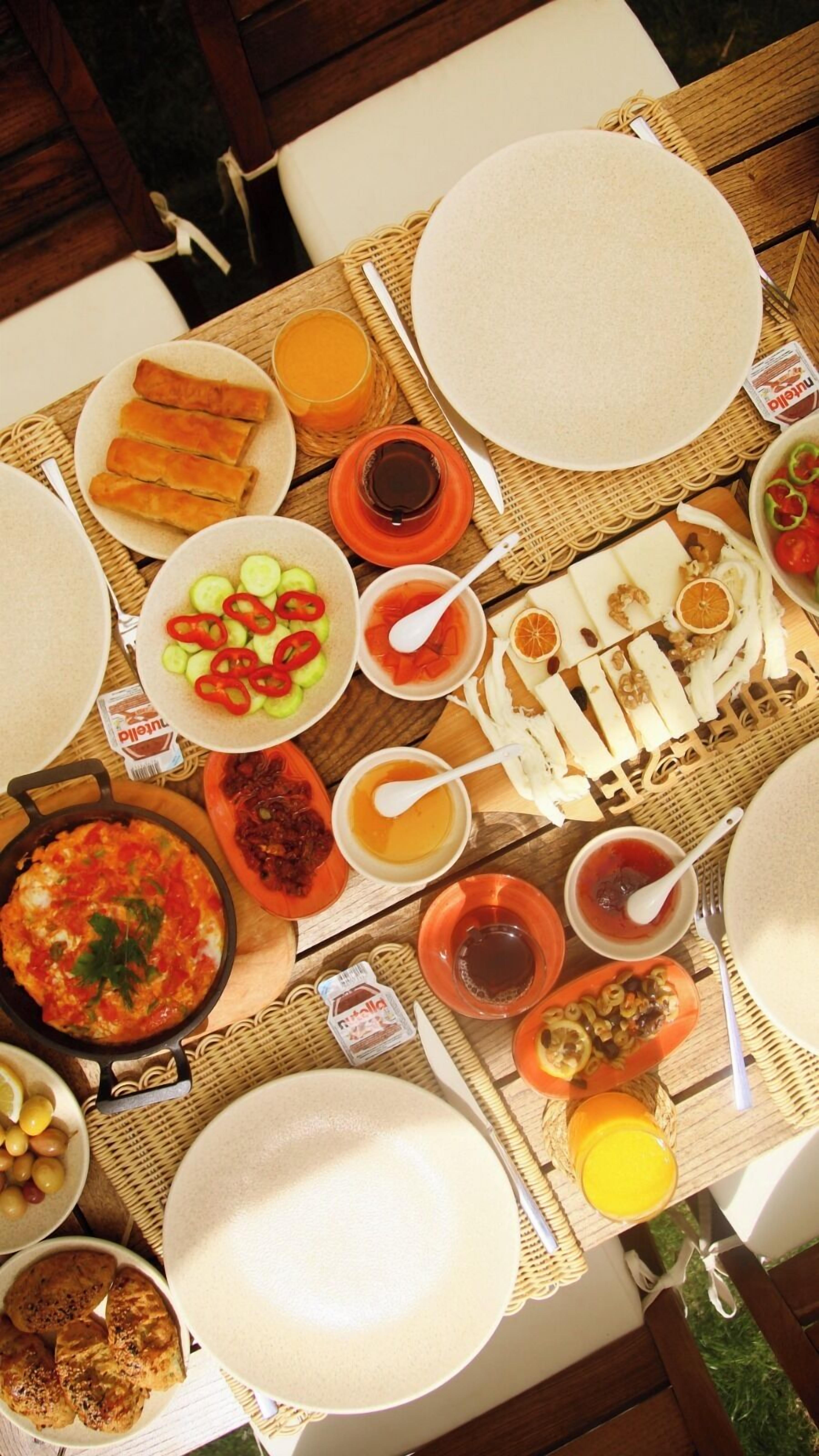 Una mesa lista para el desayuno con diferentes platos, incluyendo huevos, pan y fruta.