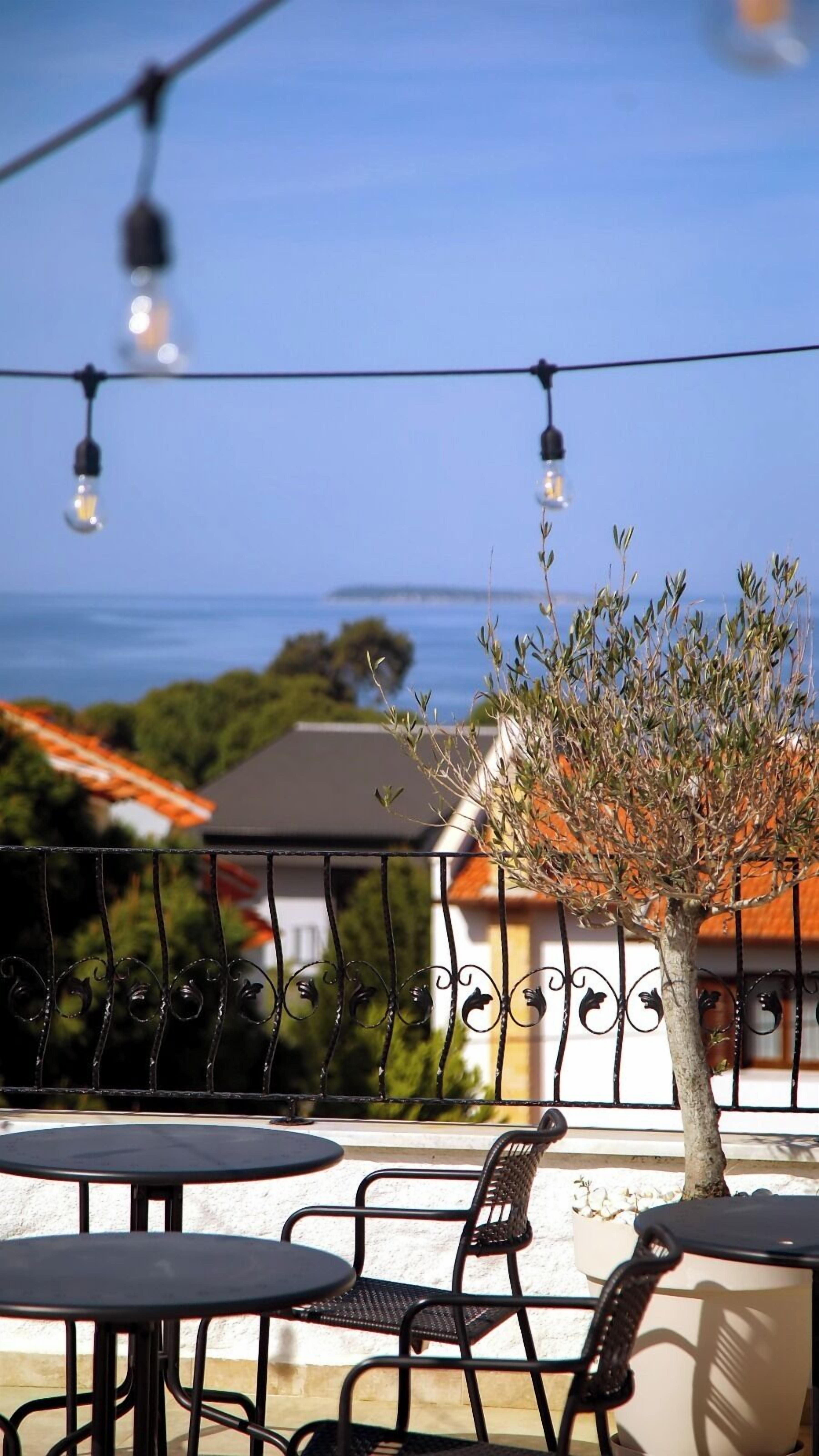 Una terraza con mobiliario exterior, luces colgantes y vistas al mar.